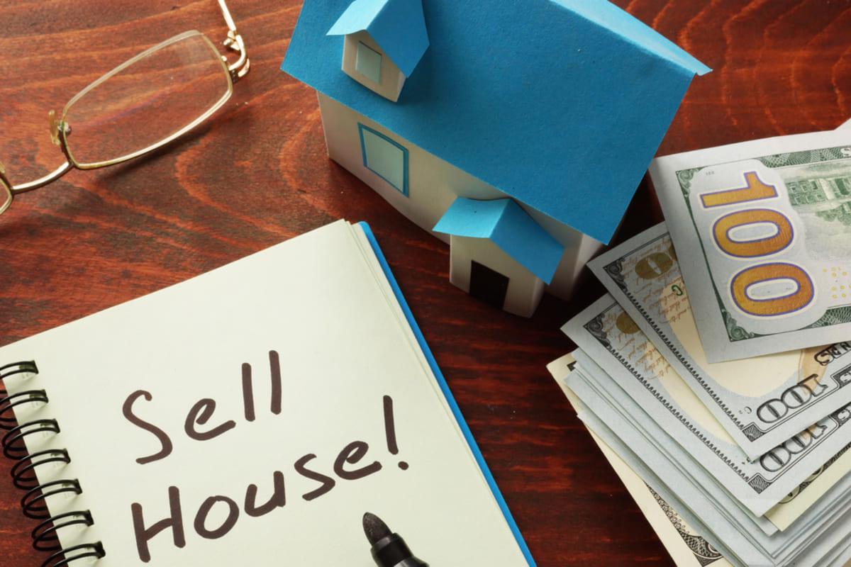 A house next to cash and a notebook that says Sell House!, buy my house for cash concept Multi-family House